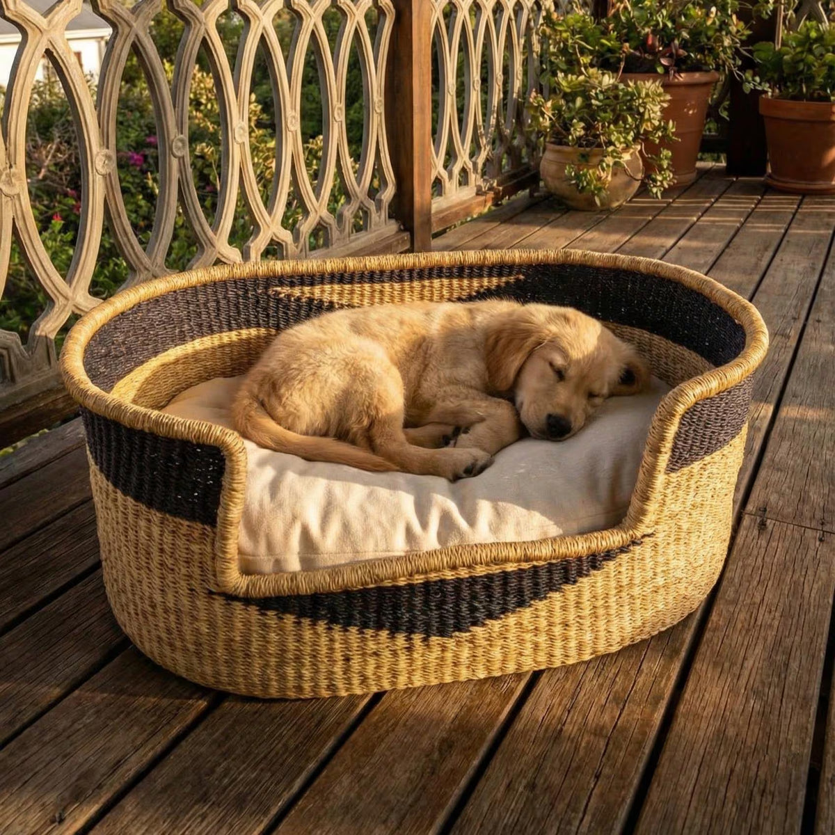 Puppy sleeping in a handwoven elephant grass dog bed on a wooden patio.